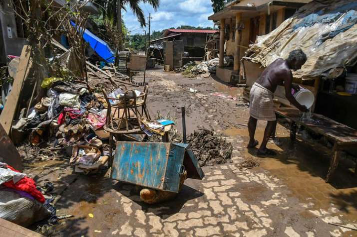 A man cleans up his house after flood water subsided, in... A man cleans up his house after flood water subsided, in...- India TV