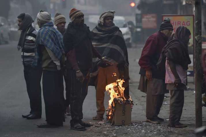 People gather around a makeshift bonfire to warm... People gather around a makeshift bonfire to warm...- India TV