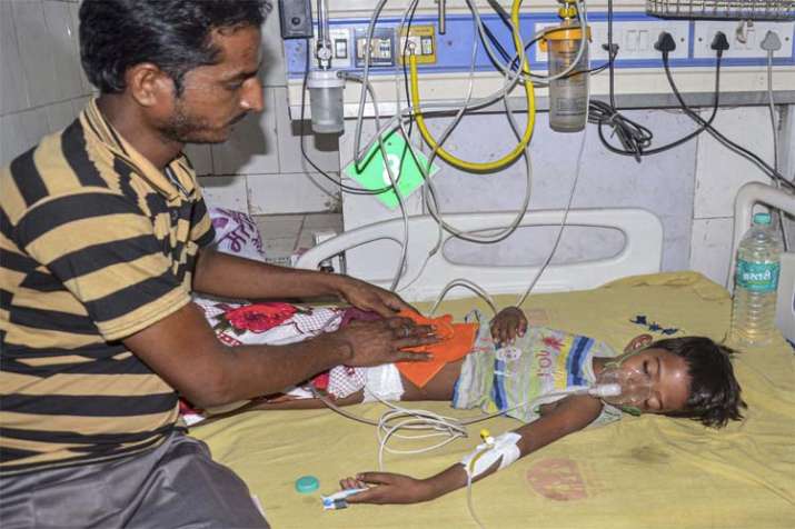 A man takes care of a child suffering from Acute Encephalitis Syndrome (AES) at a hospital in Muzaff A man takes care of a child suffering from Acute Encephalitis Syndrome (AES) at a hospital in Muzaff- India TV