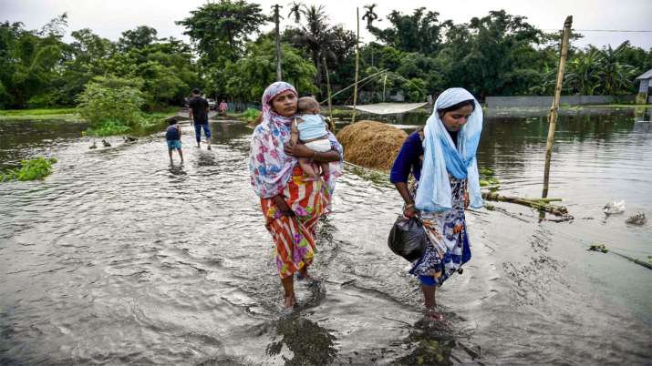 People wade through a flooded road following the incessant monsoon rainfalls at Kalgachi, in Barpeta People wade through a flooded road following the incessant monsoon rainfalls at Kalgachi, in Barpeta- India TV