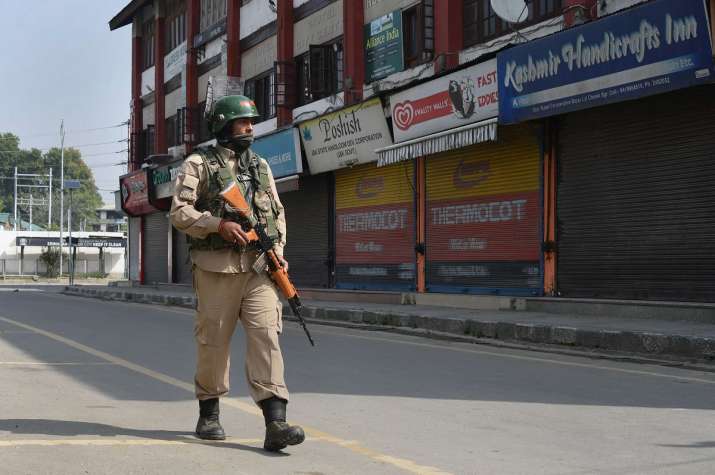 A security personnel patrols a street during... A security personnel patrols a street during...- India TV