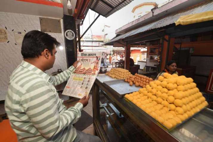 Shopkeeper reads newspaper fronted with headlines on... Shopkeeper reads newspaper fronted with headlines on...- India TV